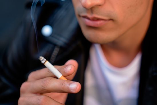 Мужчина держит в руках сигарету Мужчина курит сигарету